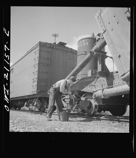 Acomita, New Mexico. Brakeman R.E. Capsey repacking a journal box of a special car as the train on the Atchison, Topeka and Santa Fe Railroad between Belen and Gallup, New Mexico waits on a siding