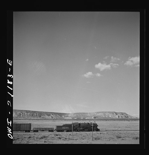 South Chaves (vicinity), New Mexico. On the Atchison, Topeka and Santa Fe Railroad between Belen and Gallup, New Mexico, passing an eastbound freight train