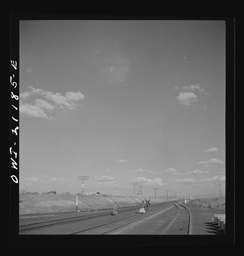 Thoreau, New Mexico. Indian woman crossing the tracks as the conductor gives the highball along the Atchison, Topeka and Santa Fe Railroad between Belen and Gallup, New Mexico