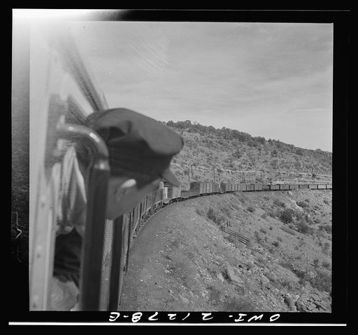 Untitled photo, possibly related to: Williams (vicinity), Arizona. A train on the Atchison, Topeka and Santa Fe Railroad between Winslow and Seligman, Arizona coming out of a tunnel through the hillside