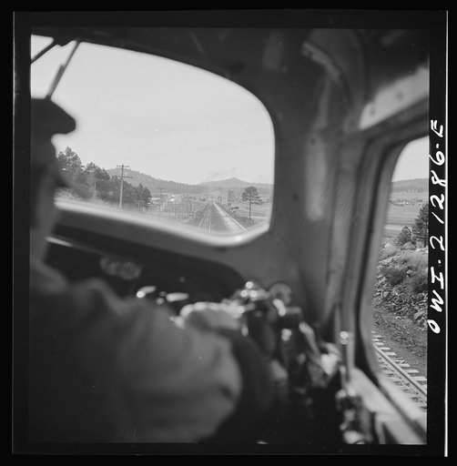 Untitled photo, possibly related to: Willliams, Arizona. The engineer, on the Atchison, Topeka and Santa Fe Railroad between Winslow and Seligman, Arizona, with his hand on the "air" as the train slows down