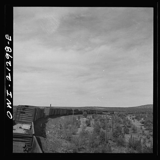 A diesel freight train on the Atchison, Topeka and Santa Fe Railroad between Winslow and Seligman, Arizona going down the mountains from Supai to Ash Fork, Arizona, a drop of about 1600 feet. A brakeman is riding on the top of the car. He stays on as far as Ash Fork, to operate the retainers