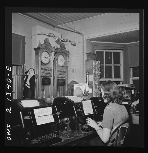 Untitled photo, possibly related to: Seligman, Arizona. Teletype operator in the telegraph office of the Atchison, Topeka, and Santa Fe Railroad. The time here changes from Mountain to Pacific time