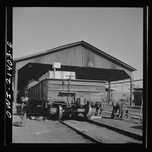 Untitled photo, possibly related to: Needles, California. Workmen jacking up a car at the rip tracks in the Atchison, Topeka, and Santa Fe Railroad yard