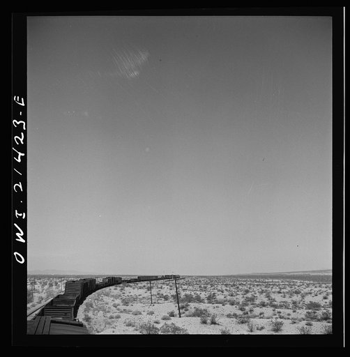 Untitled photo, possibly related to: Goffs (vicinity), California. A diesel freight train going around a curve on the Atchison, Topeka, and Santa Fe Railroad between Needles and Barstow, California