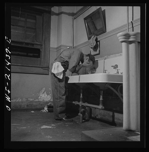 Barstow, California. Railroad worker washing up in the wash room of the reading room in the Atchison, Topeka, and Santa Fe Railroad yard