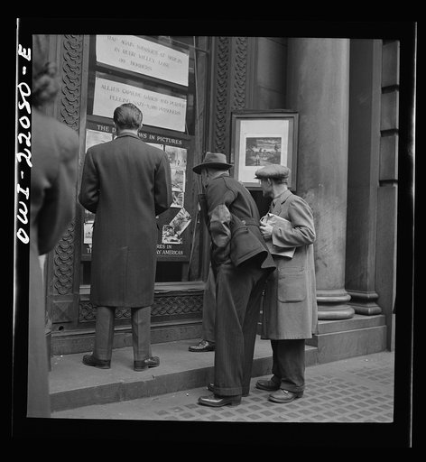 Baltimore, Maryland. Reading news bulletins and looking at the news pictures outside the Baltimore News building