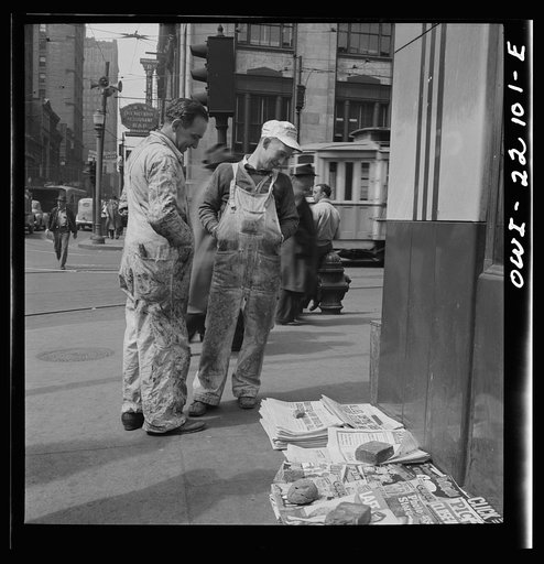 Baltimore, Maryland. Workers reading the newsstand papers while waiting for a trolley after work