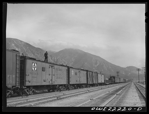 Cajon, California. Swing brakeman riding on top of the Atchison, Topeka, and Santa Fe Railroad train. Brakemen ride the trains in this way during the entire descent from Summit to San Bernardino