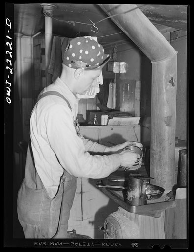 Untitled photo, possibly related to: Atchison, Topeka, and Santa Fe Railroad. Brakeman L.E. Capsey preparing a meal in the caboose enroute to Gallup, New Mexico