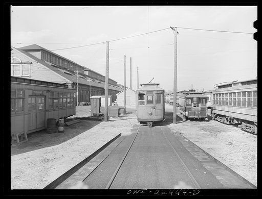 Untitled photo, possibly related to: Baltimore, Maryland. The yard of the Washington terminal, maintenance plant of the Baltimore Transit Company. From left to right: old trolley made into a smoker for employees; a work car; and old horse car. The Baltimore Trust building on the horizon