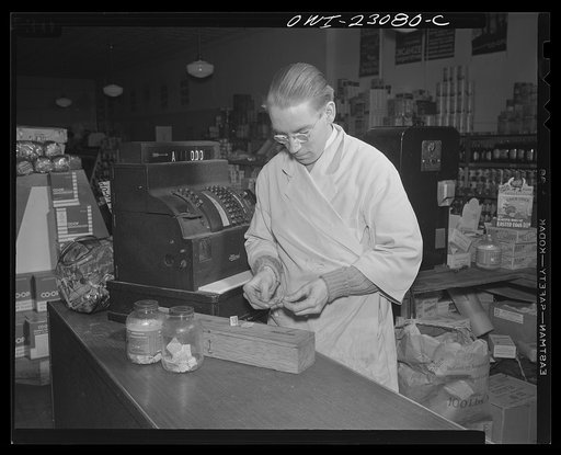 Untitled photo, possibly related to: Washington, D.C. Coffee jars with slots in the lids are used for sugar and coffee stamps. A homemade plywood box with dotted cover and compartments is used for blue stamps, which must be surrendered by customers under the point system