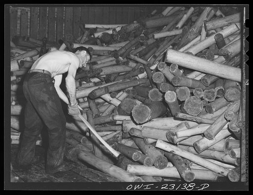 Untitled photo, possibly related to: Lufkin, Texas. Southland paper mill. Moving logs onto a conveyor belt which carries them to grinders, where they are made into ground wood