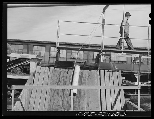 Untitled photo, possibly related to: Lufkin, Texas. Southland paper mill. Barked logs falling into a wood bin where they are stored until ready for the grinding machine