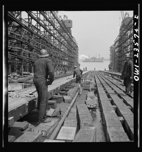 Bethlehem-Fairfield shipyards, Baltimore, Maryland. Workers removing grease from the ways after a ship launching ceremony