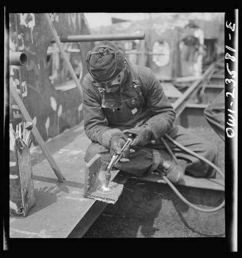 Untitled photo, possibly related to: Bethlehem-Fairfield shipyards, Baltimore, Maryland. Burning a hole in a lifting ship