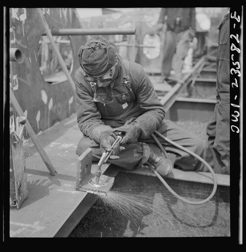 Bethlehem-Fairfield shipyards, Baltimore, Maryland. Burning a hole in a lifting ship