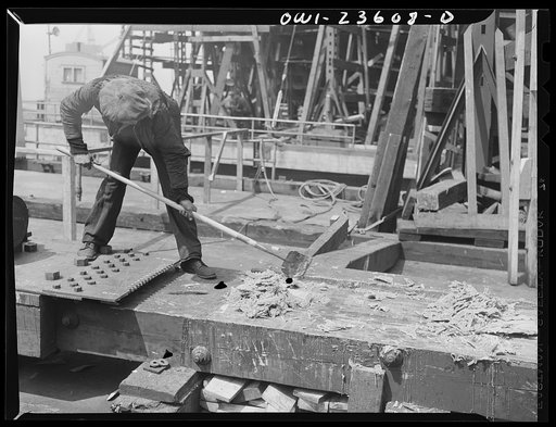 Bethlehem-Fairfield shipyards, Baltimore, Maryland. Scraping grease from the ways after a launching ceremony