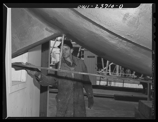 Bethlehem-Fairfield shipyards, Baltimore, Maryland. Painting a protection bar on the stem of a ship just before launching her