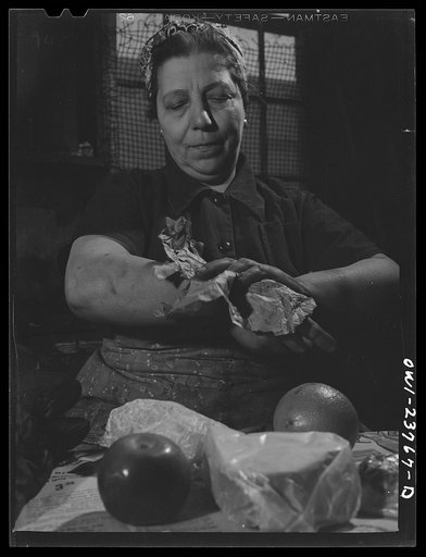 Buffalo, New York. Italian-American woman wiping the grease off her hands with paper before eating her lunch which she brought from home in the shop of the New York Car Wheel Company where she is a combination hooker (one who hooks things onto crane chains) and grinder
