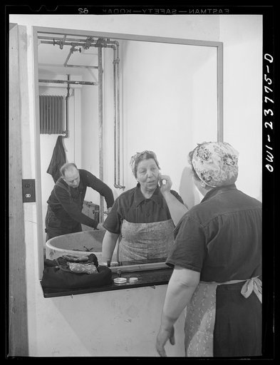 Buffalo, New York. Italian-American woman, grinder and hooker at the New York Car Wheel Company, powdering her nose. This concern has only recently hired women, and the women's locker room is still unfinished. A plumber can be seen in the background installing a sink. This situation is typical of ma