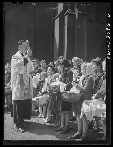 Buffalo, New York. Priest blessing baskets of food outside the church in the Polish community on the day before Easter. The ceremony celebrates the breaking of Lent in fasting. The food is eaten on Easter day