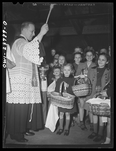 Untitled photo, possibly related to: Buffalo, New York. Priest blessing baskets of food outside the church in the Polish community on the day before Easter. The ceremony celebrates the breaking of Lent in fasting. The food is eaten on Easter day
