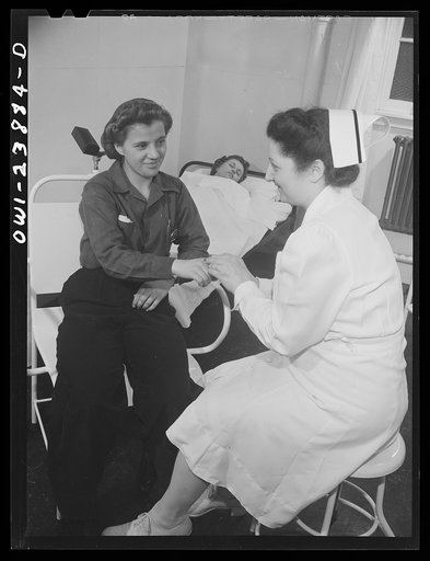 Untitled photo, possibly related to: Buffalo, New York. A nurse in the first aid room at the Ross Heater plant bandaging a slight finger injury. Another woman worker rests in the background