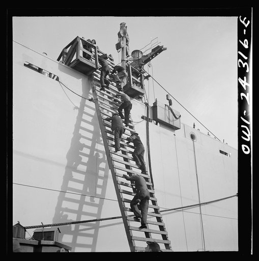Bethlehem-Fairfield shipyards, Baltimore, Maryland. Workers descending a ladder at the outfitting pier