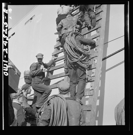 Bethlehem-Fairfield shipyards, Baltimore, Maryland. Workers on a ladder at the outfitting pier