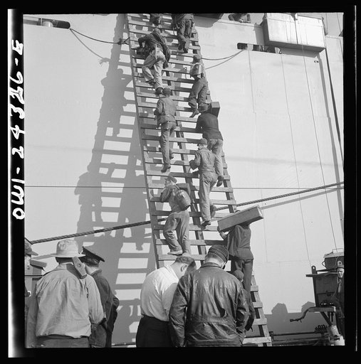 Bethlehem-Fairfield shipyards, Baltimore, Maryland. Workers on a ladder at the outfitting pier