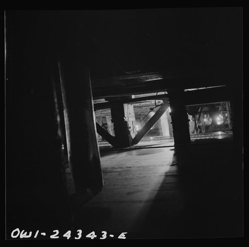 Bethlehem-Fairfield shipyards, Baltimore, Maryland. Looking through the shoring under a ship at night
