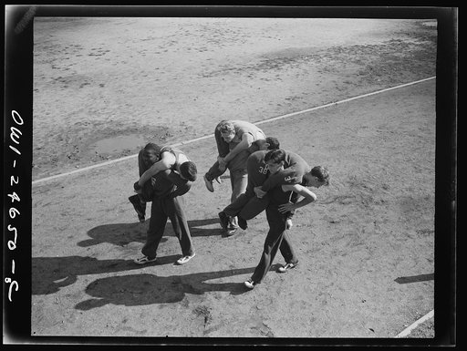 Benjamin Franklin High School, New York, New York. Boys in the "commando" course, part of the physical education program, learning the fireman's "carry," or the correct method of carrying a wounded comrade
