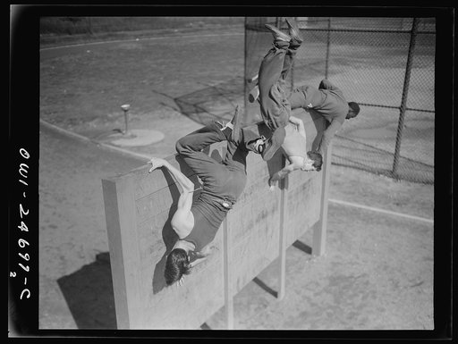Untitled photo, possibly related to: Flushing High School, Queens, New York, New York. Scaling an eight foot obstacle at top speed, part of the "commando" training course offered by the physical education department, which puts the boys who finish the course in top physical condition, if needed by t