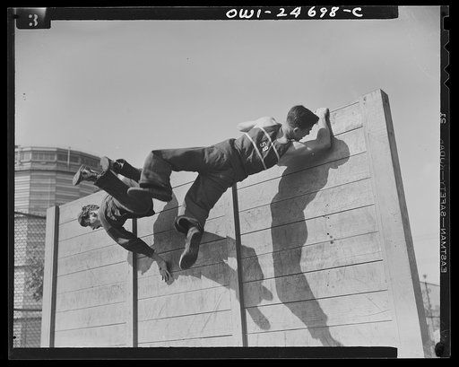 Untitled photo, possibly related to: High school Victory Corps. The "commando" training course offered by the physical education department of Flushing High School, Queens, New York, includes scaling an eight-foot obtacle at top speed. When the boys finish the course they will be in top physical con