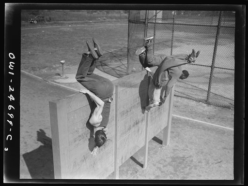 Flushing High School, Queens, New York, New York. Scaling an eight foot obstacle at top speed, part of the "commando" training course offered by the physical education department, which puts the boys who finish the course in top physical condition, if needed by the armed forces