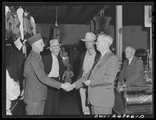 San Augustine, Texas. A.J. Wood, owner of the clothing store, shaking hands with a soldier home on furlough