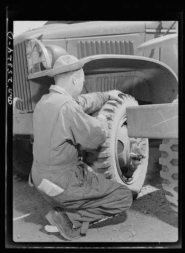 Untitled photo, possibly related to: Holabird ordnance depot, Baltimore, Maryland. A soldier removing a tack from a United States Army truck tire. Constant fire inspection is required of all drivers at the depot