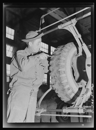 Holabird ordnance depot, Baltimore, Maryland. In the recapping shop, after visual inspection, the tire is put in a tire spreader for thorough inside and outside inspection. Here a soldier is using a probe to remove a nail from the tire