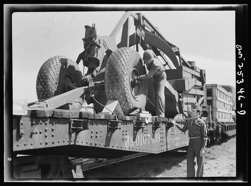 Holabird ordnance depot, Baltimore, Maryland. An officer checking the air pressure of the giant tires on LeTourneau road scrapers which are being sent overseas. Pressure must be ten pounds above normal load to keep tires in best condition during the journey