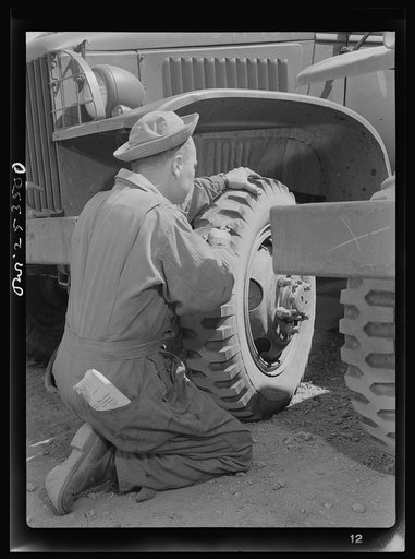 Holabird ordnance depot, Baltimore, Maryland. A soldier removing a tack from a United States Army truck tire. Constant fire inspection is required of all drivers at the depot