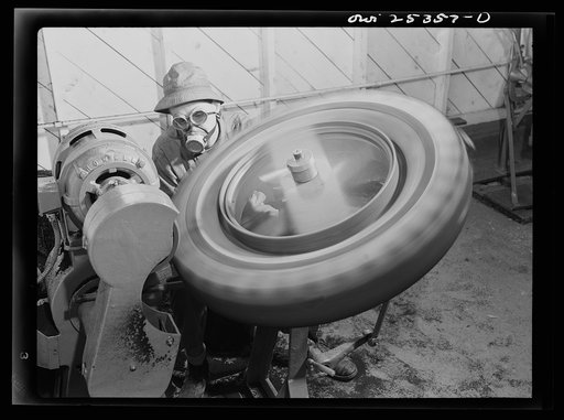 Holabird ordnance depot, Baltimore, Maryland. The buffing room in the recapping shop. Before being recapped, tires must be buffed. The rasp buffs rubber off. This rubber is afterwards collected for salvage