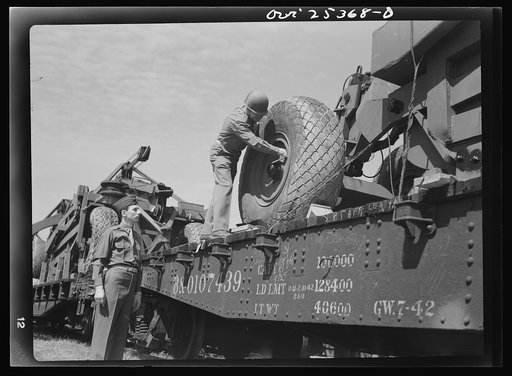 Holabird ordnance depot, Baltimore, Maryland. An officer checking the air pressure of giant tires on LeTourneau roadscrapers to be shipped overseas. Pressure must be ten pounds above normal load to keep tires in best condition during the journey
