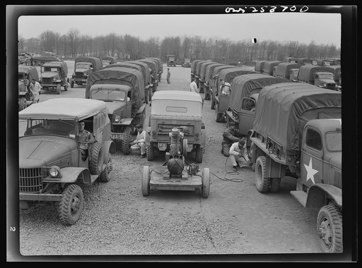 Holabird ordnance depot, Baltimore, Maryland. A convoy prepares for departure by checking all tires on all vehicles. Air pressure must be at the required poundage on every tire before the convoy is allowed to leave. Vehicle in the center has mobile air pressure pump attached to trailer