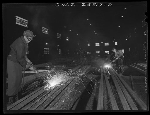 Untitled photo, possibly related to: Buffalo, New York. In the finishing department of Republic Steel. Gladys Chase (left), former beautician, using an acetylene torch to burn defects from a twenty-foot steel billet which will later be shaped into a machine gun barrel. It takes six months to learn t
