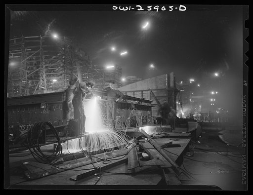 A burner employs an acetyline torch effectively in cutting away metal on a sub-assembly operation. The burner department which renders service to other departments is in charge of much of this work. Women are often employed in this phase of the work