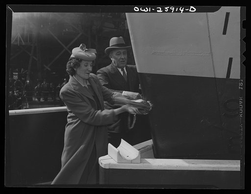 Bethlehem-Fairfield shipyards, Baltimore, Maryland. Swinging a champagne bottle at a ship to christen it