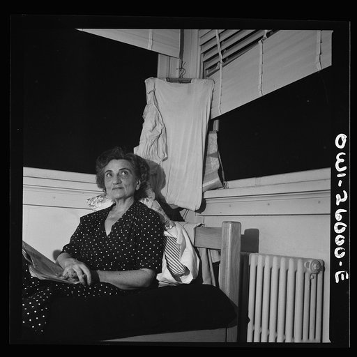 Untitled photo, possibly related to: Arlington, Virginia. An older resident reading the paper and listening to the radio in her room at Idaho Hall, Arlington Farms, a residence for women who work in the U.S. government for the duration of the war