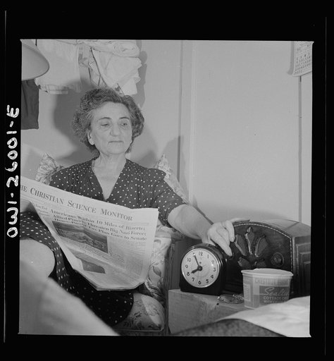 Arlington, Virginia. An older resident reading the paper and listening to the radio in her room at Idaho Hall, Arlington Farms, a residence for women who work in the U.S. government for the duration of the war