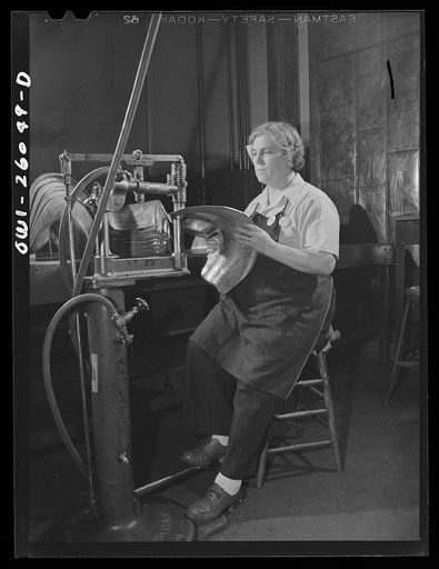 Bell Aircraft Corporation, Niagara Falls, New York. Metal stretching on a burring machine. These airplane parts have just come through a drop press and this machine takes out the bumps. Worker wears safety shoes, which have a metal plate inside the toe for protection